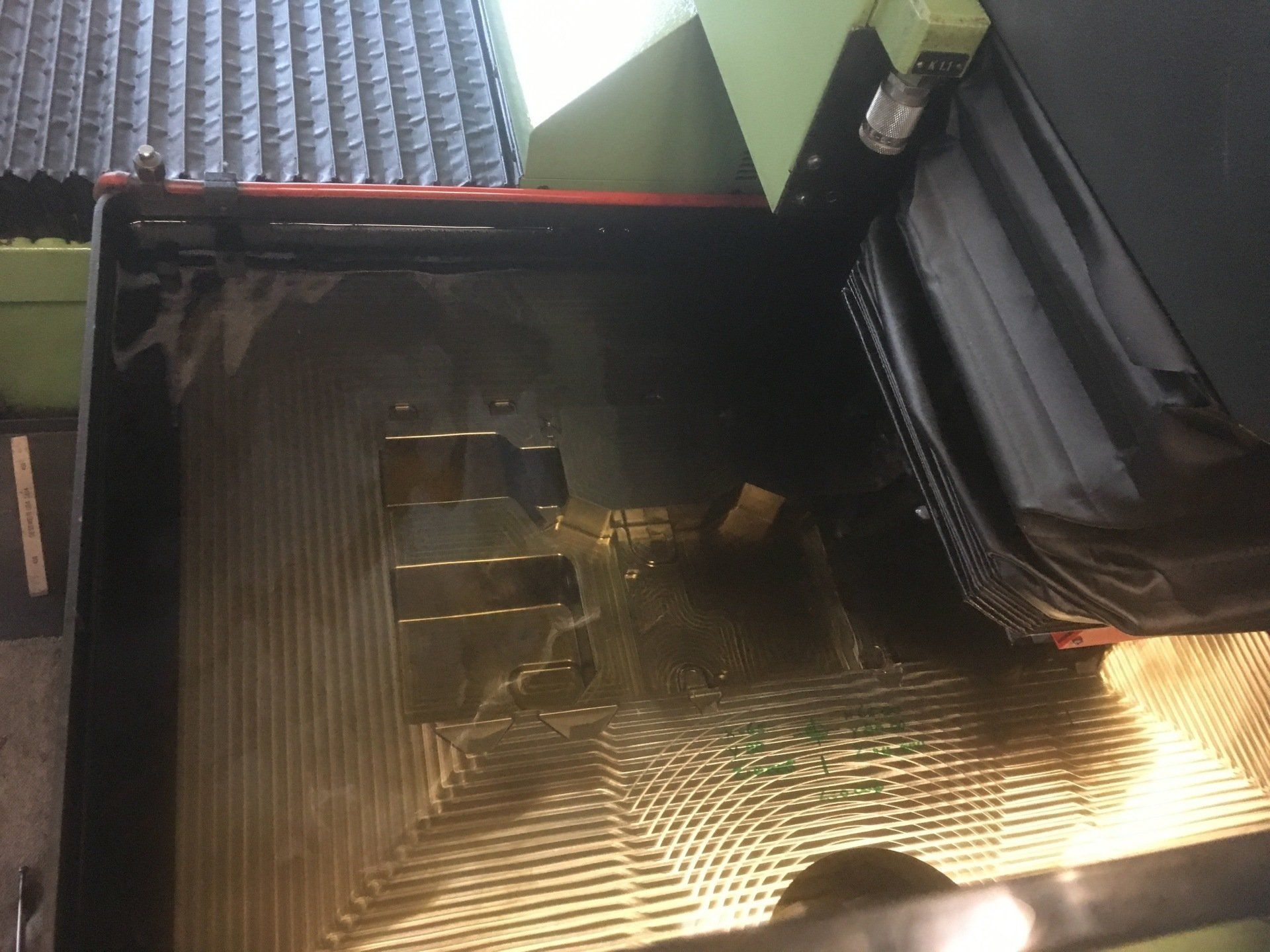 Een machine snijdt een stuk metaal op een tafel.