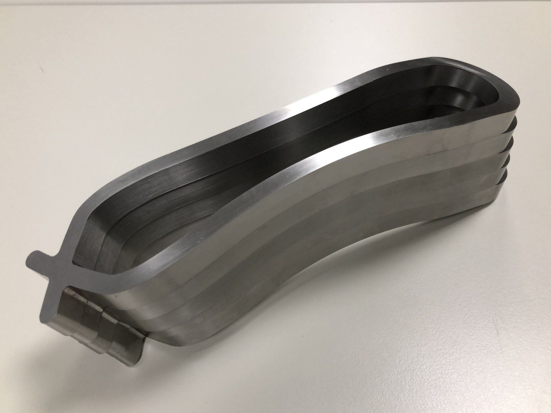 Een metalen voorwerp ligt op een wit oppervlak.