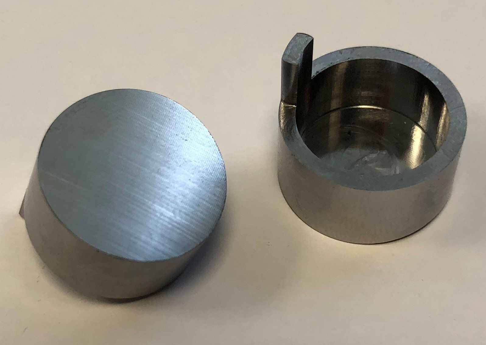 Twee metalen cilinders staan ​​naast elkaar op een wit oppervlak.