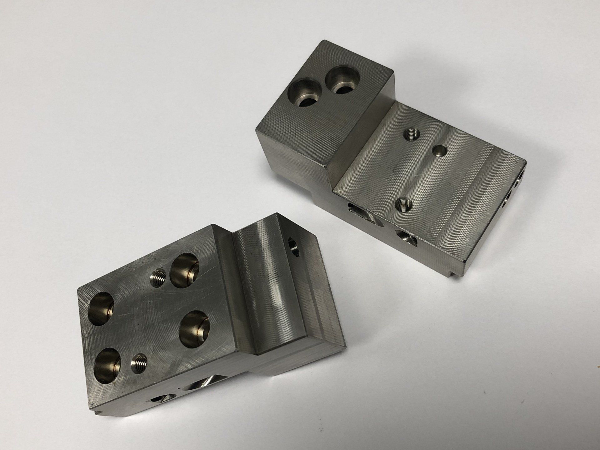 Twee stukken metaal liggen op een wit oppervlak.