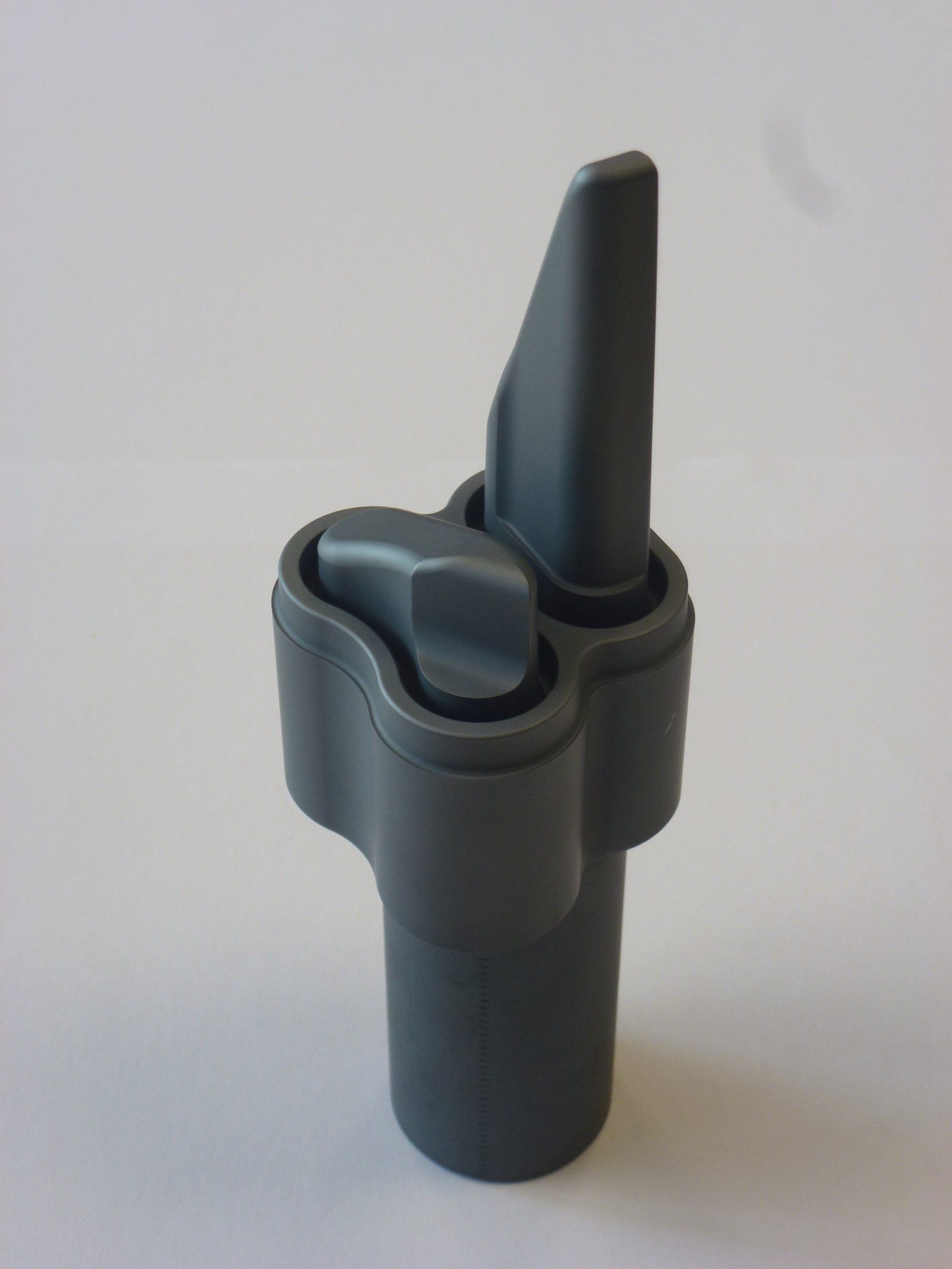 Een grijs voorwerp met een puntig uiteinde ligt op een wit oppervlak