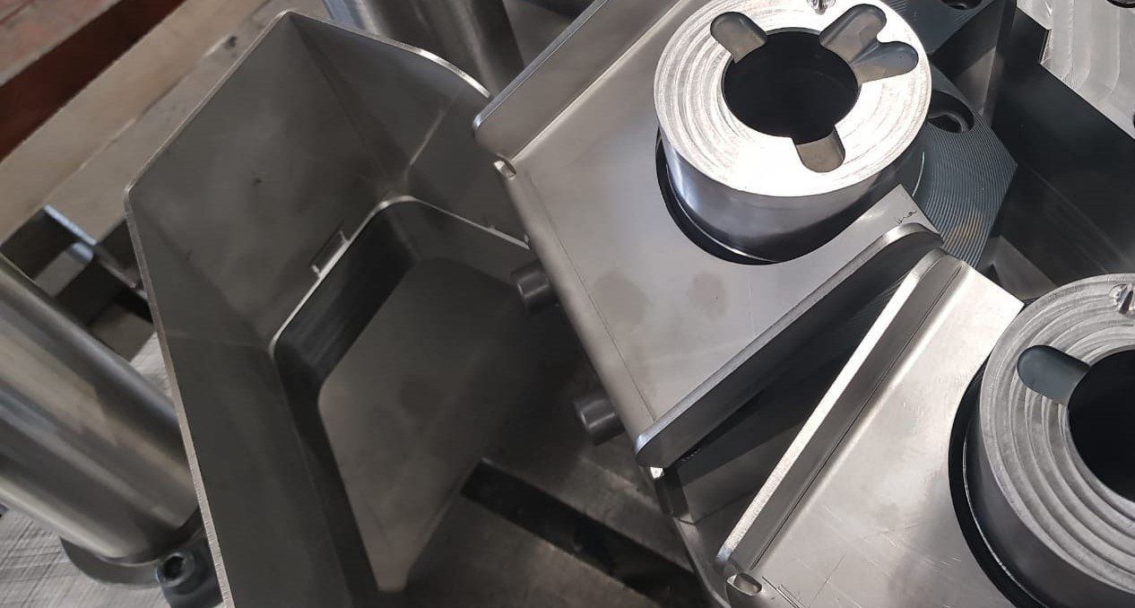 Een aantal stukken metaal liggen op elkaar op een tafel.