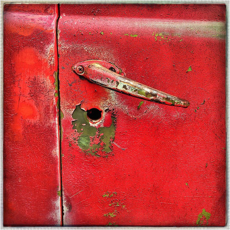 A red door with a handle and a hole in it