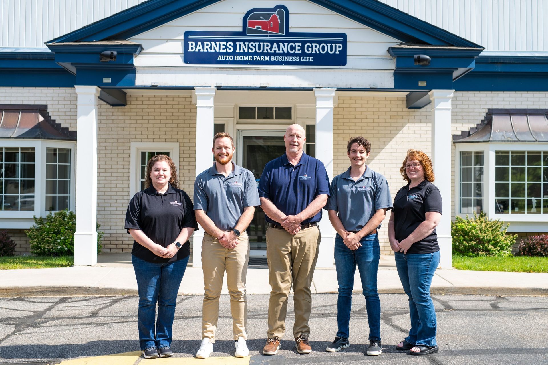 Barnes Insurance Group team poses in front of their office. Five people in casual attire stand smiling.