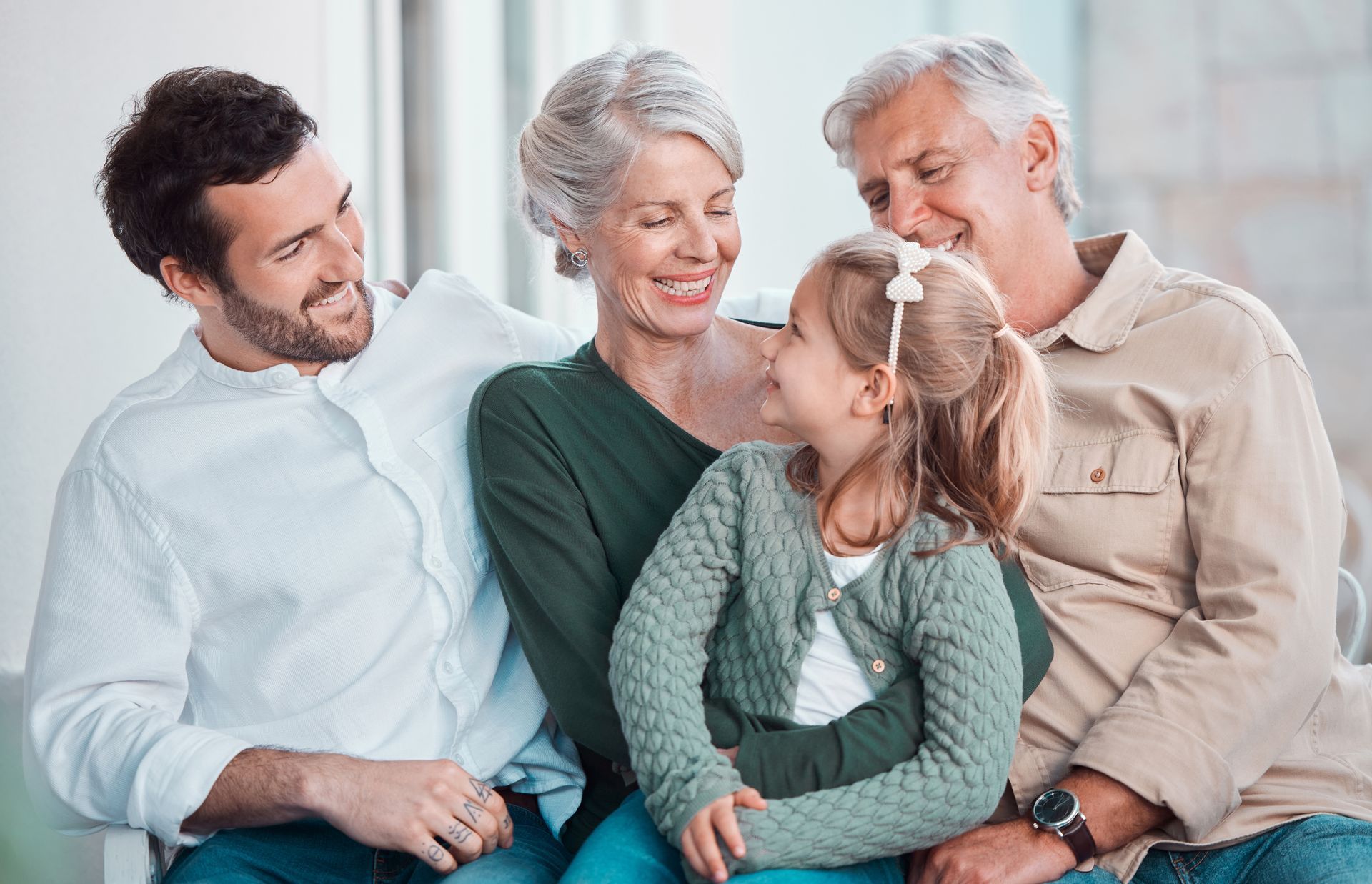 Family of four smiles together indoors on a couch.