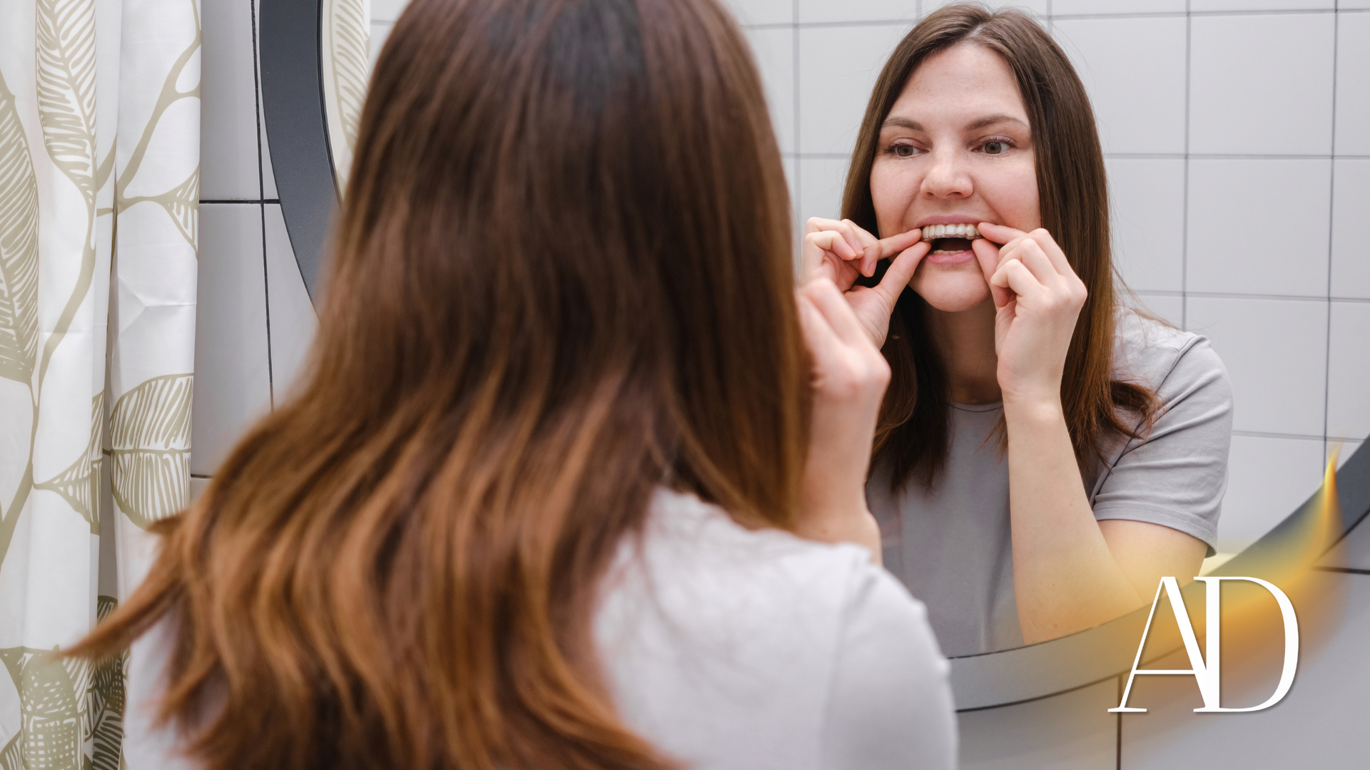 A woman is brushing her teeth in front of a mirror.