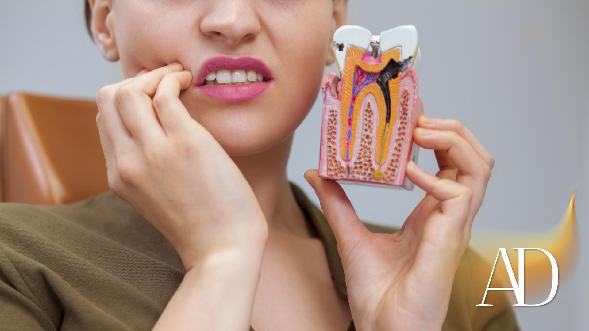 A woman is holding a model of a tooth in front of her mouth.