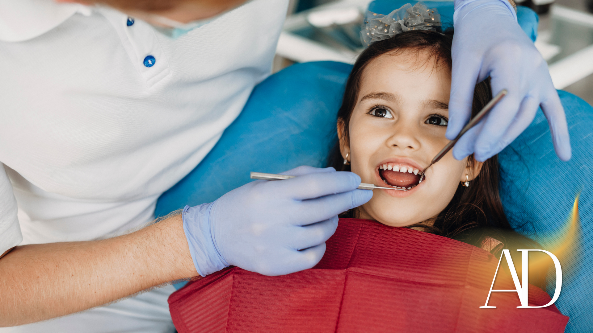 A little girl is sitting in a dental chair getting her teeth examined by a dentist.