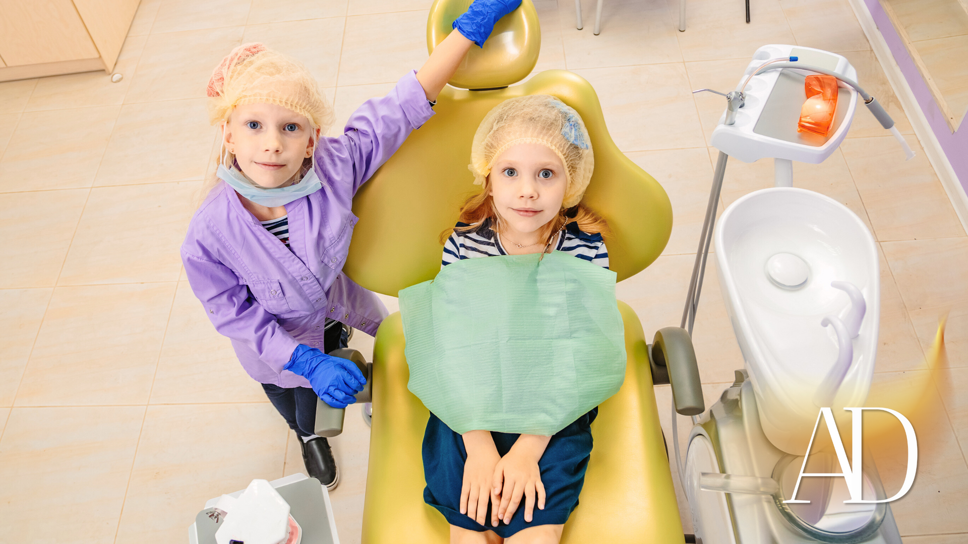 A little girl is sitting in a dental chair while a dentist examines her teeth.