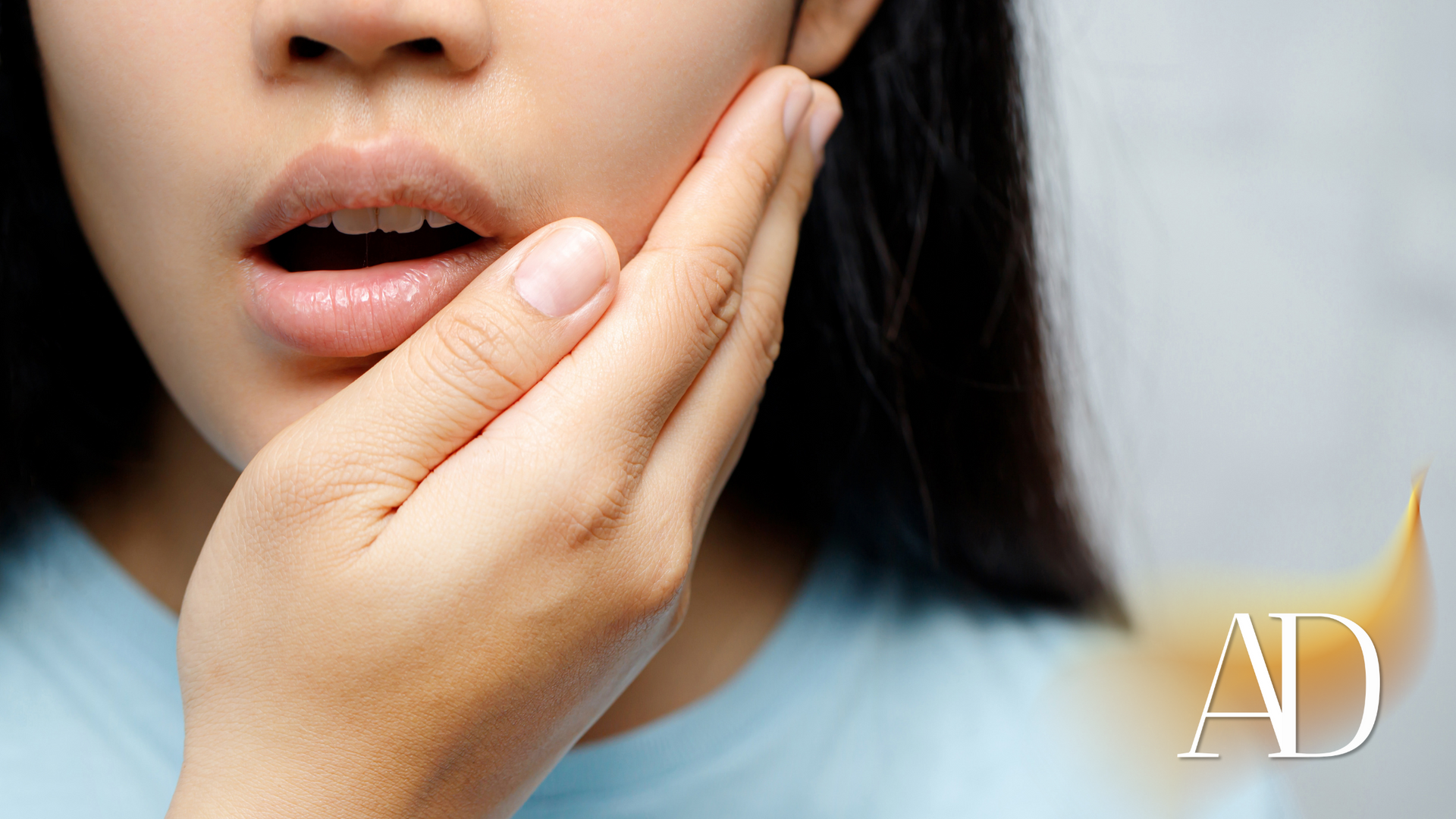 A woman is holding her face in pain because of a toothache.