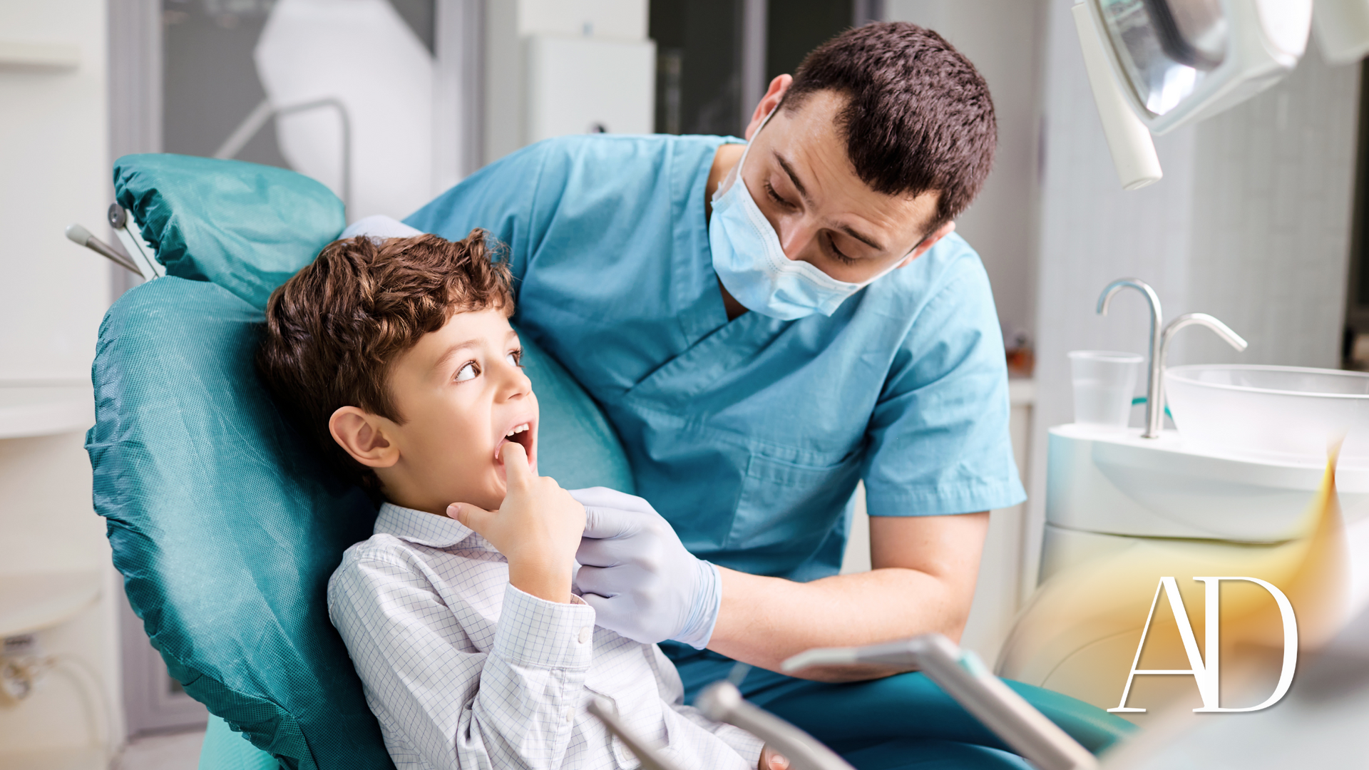 A young boy is sitting in a dental chair talking to a dentist.