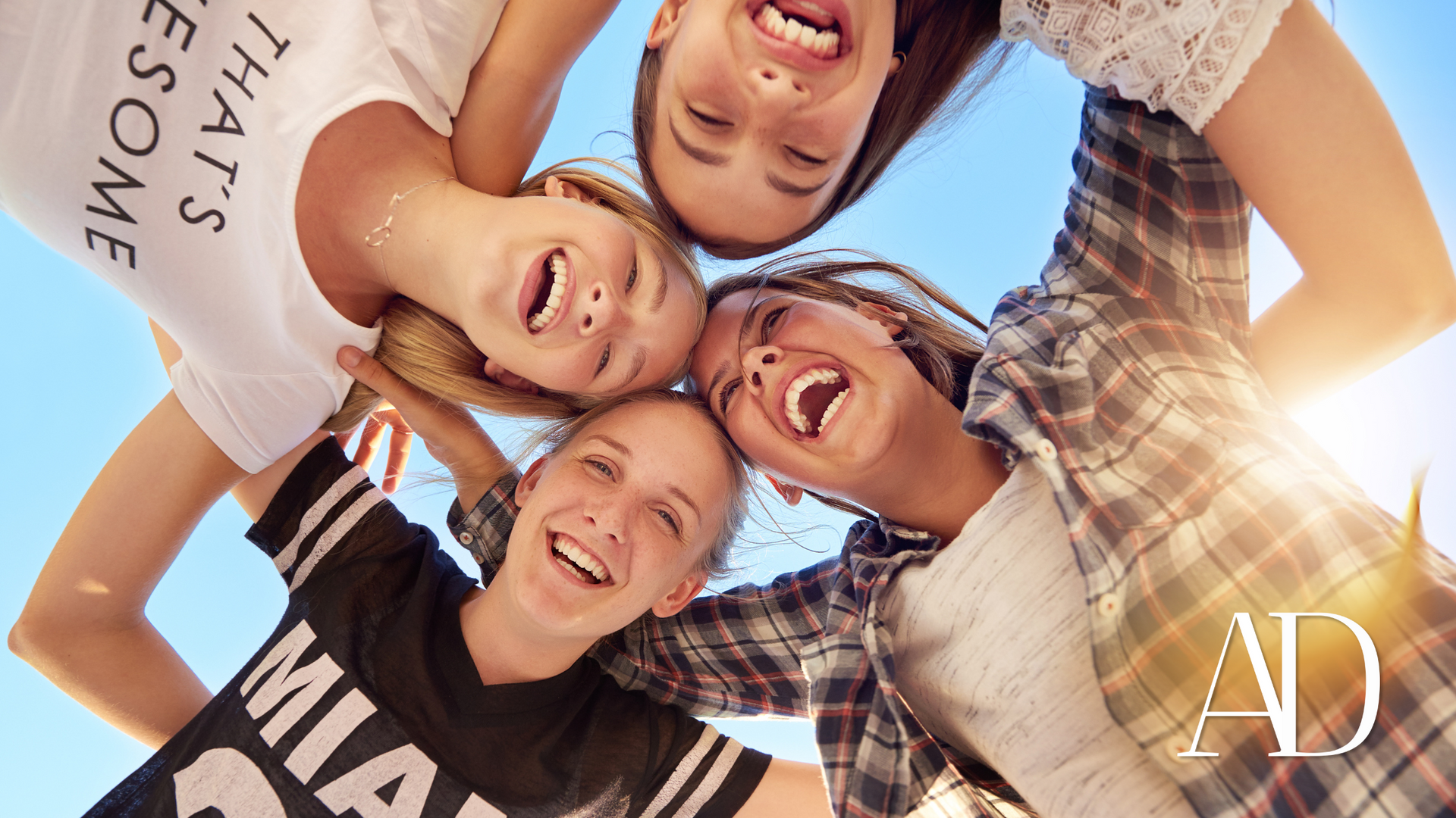 A group of young girls are standing in a circle and smiling.