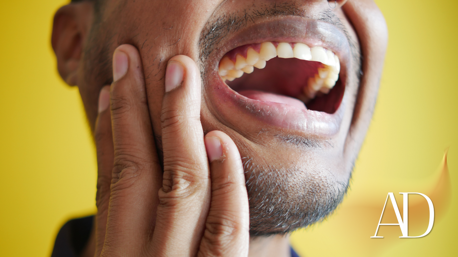A man is holding his face in pain because he has a toothache.