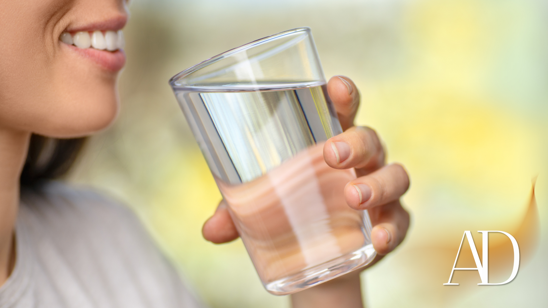 A woman is drinking a glass of water.