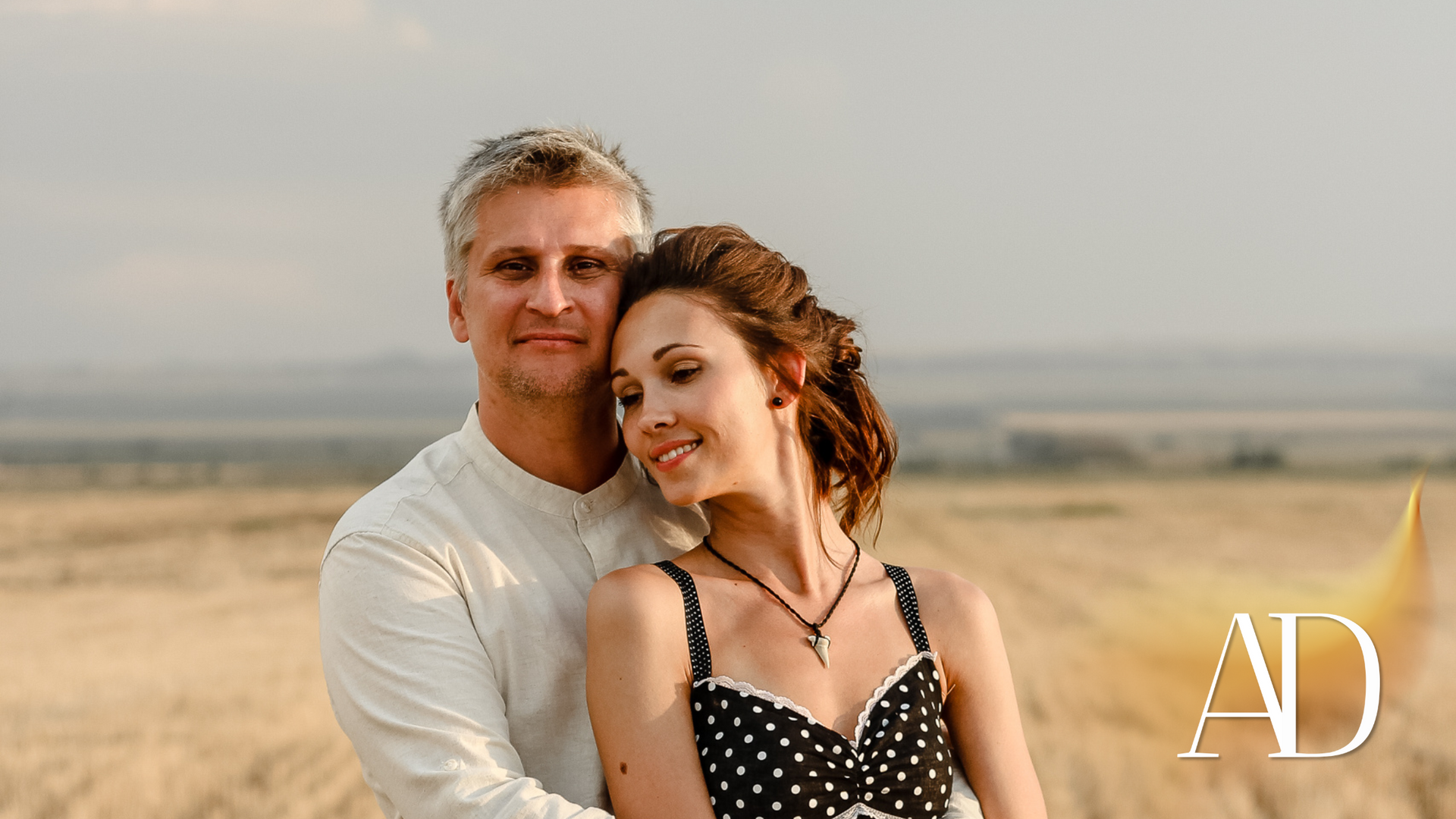 A man and a woman are hugging each other in a field.