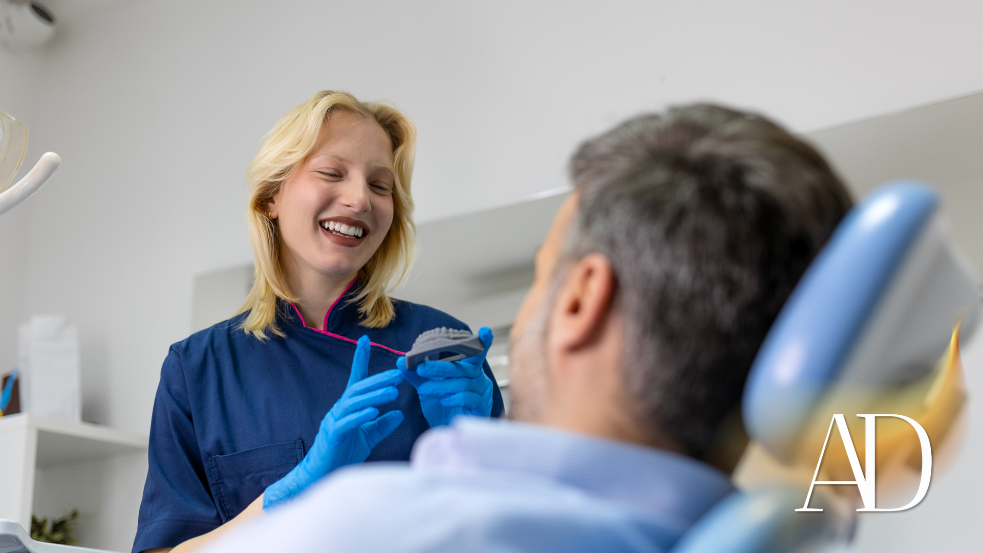 A woman is talking to a man in a dental chair.