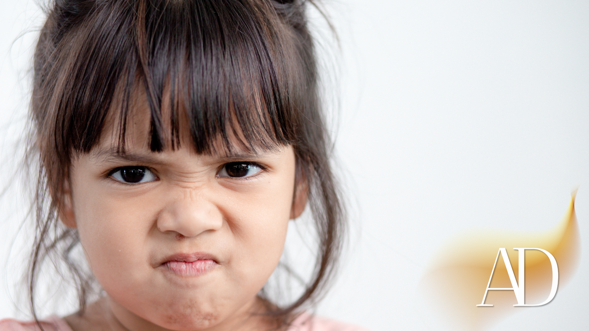 A little girl is making an angry face.