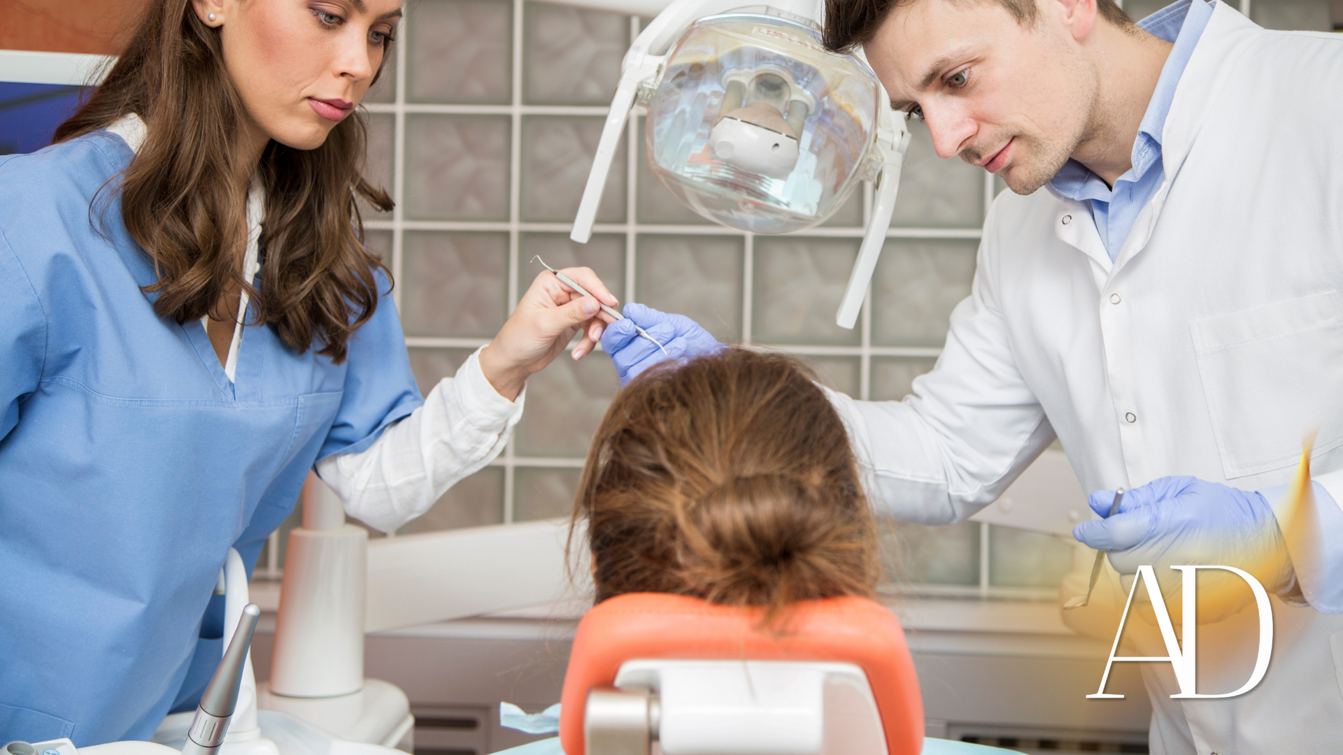 A dentist and a nurse are examining a patient 's teeth in a dental office.