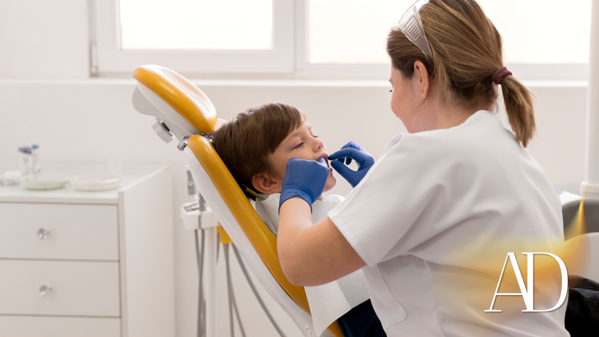 A dentist is examining a young boy 's teeth in a dental chair.