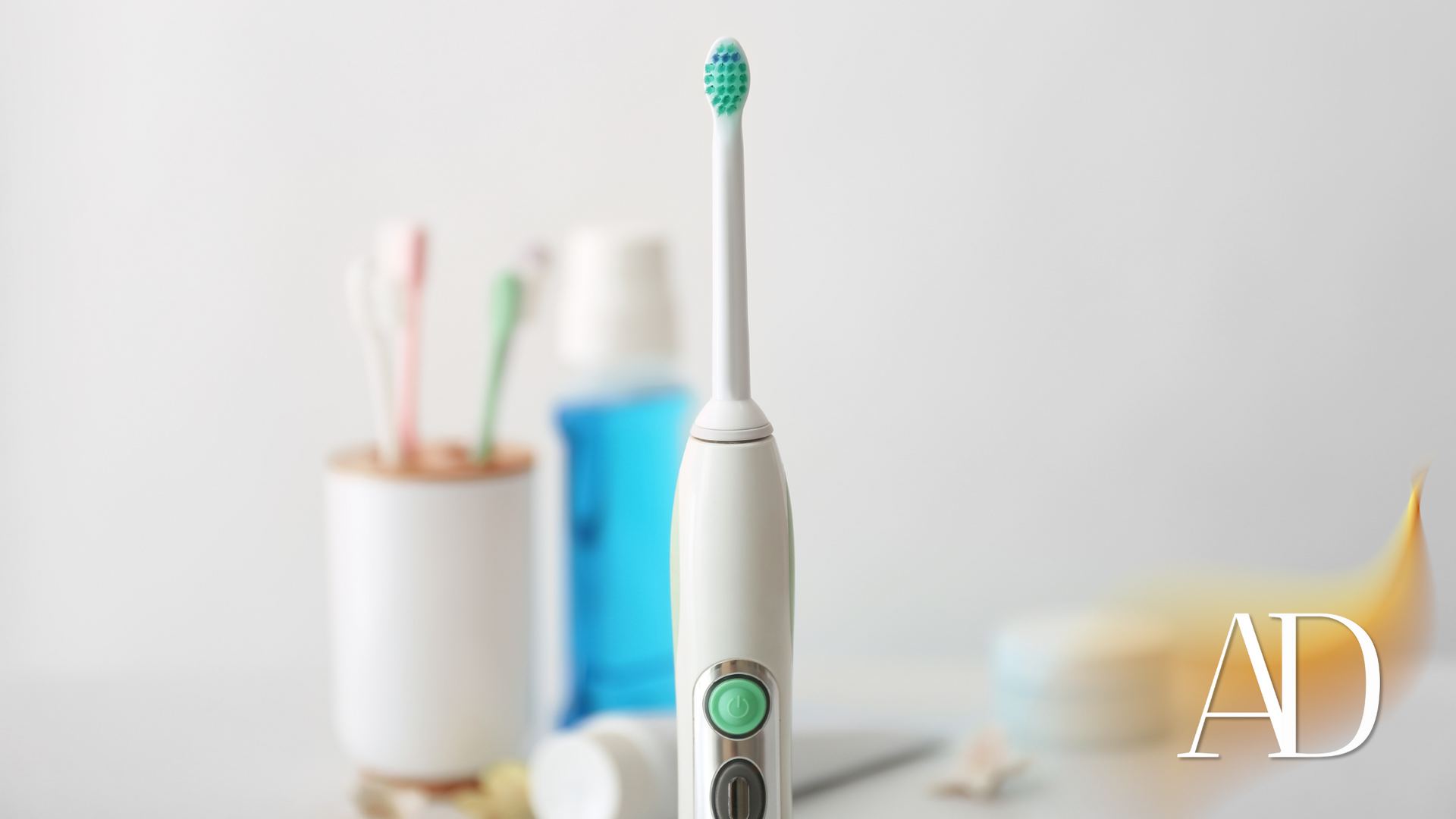 An electric toothbrush is sitting on a table next to a toothbrush holder.