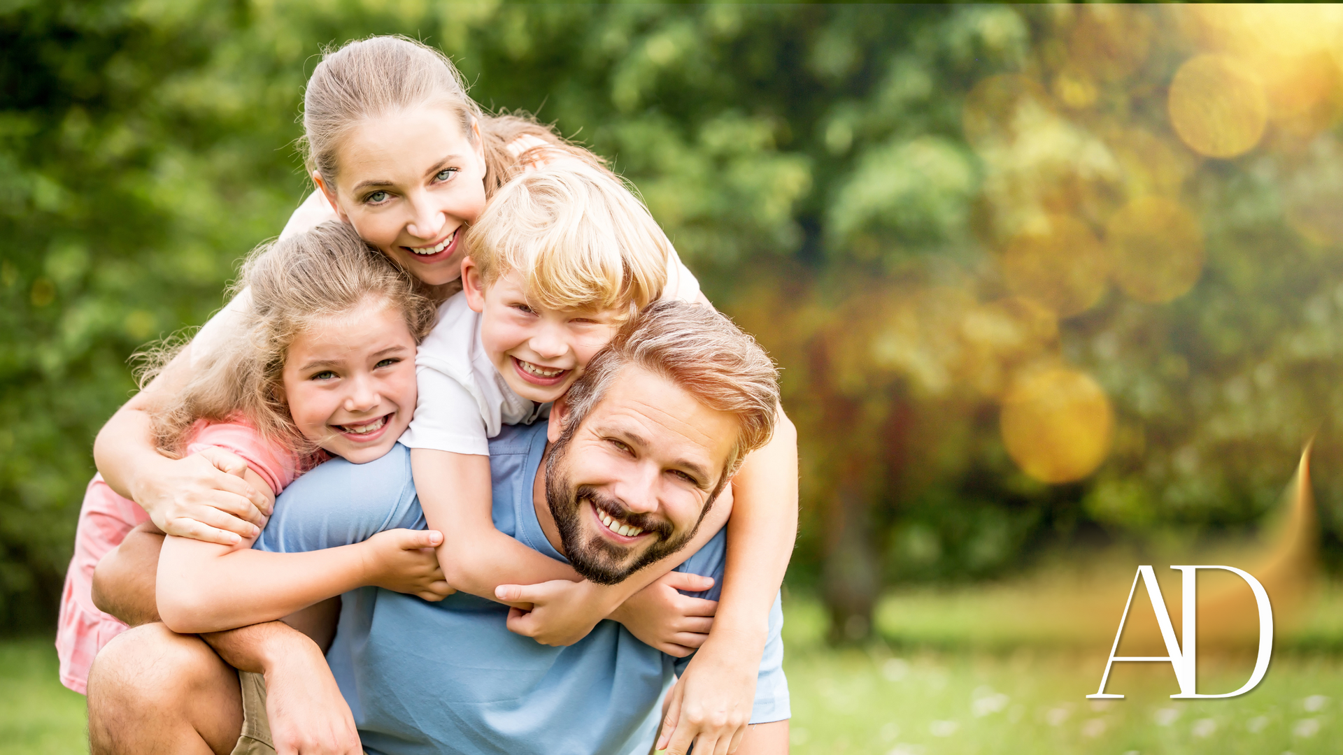 A man is carrying three children on his back in a park.