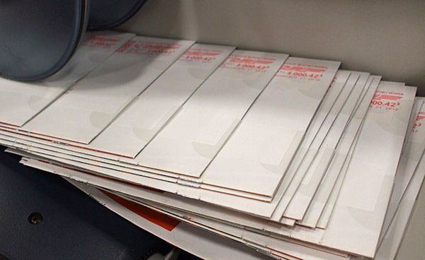Stack of white envelopes with red markings.