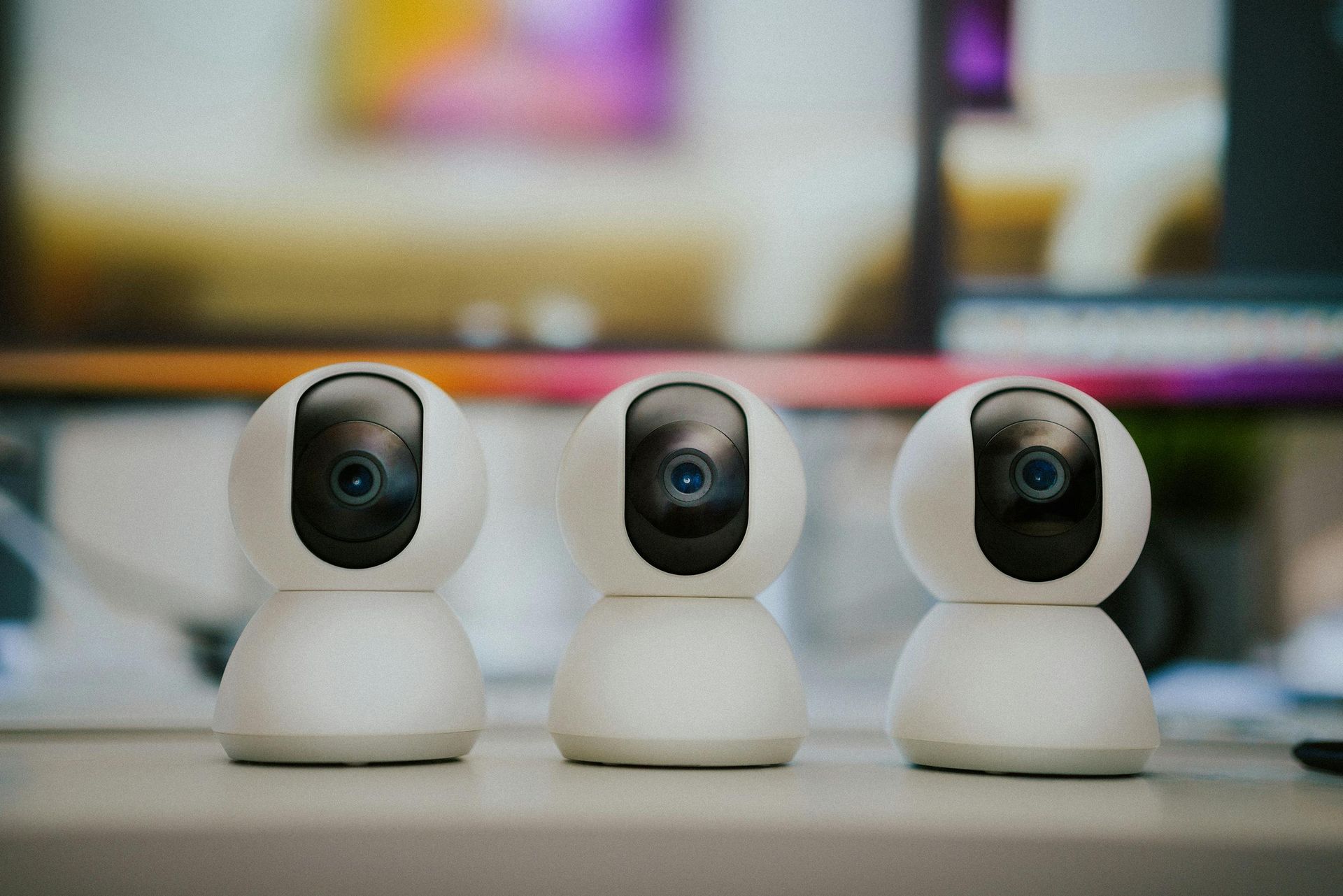 Three white security cameras lined up on a table with a blurred background