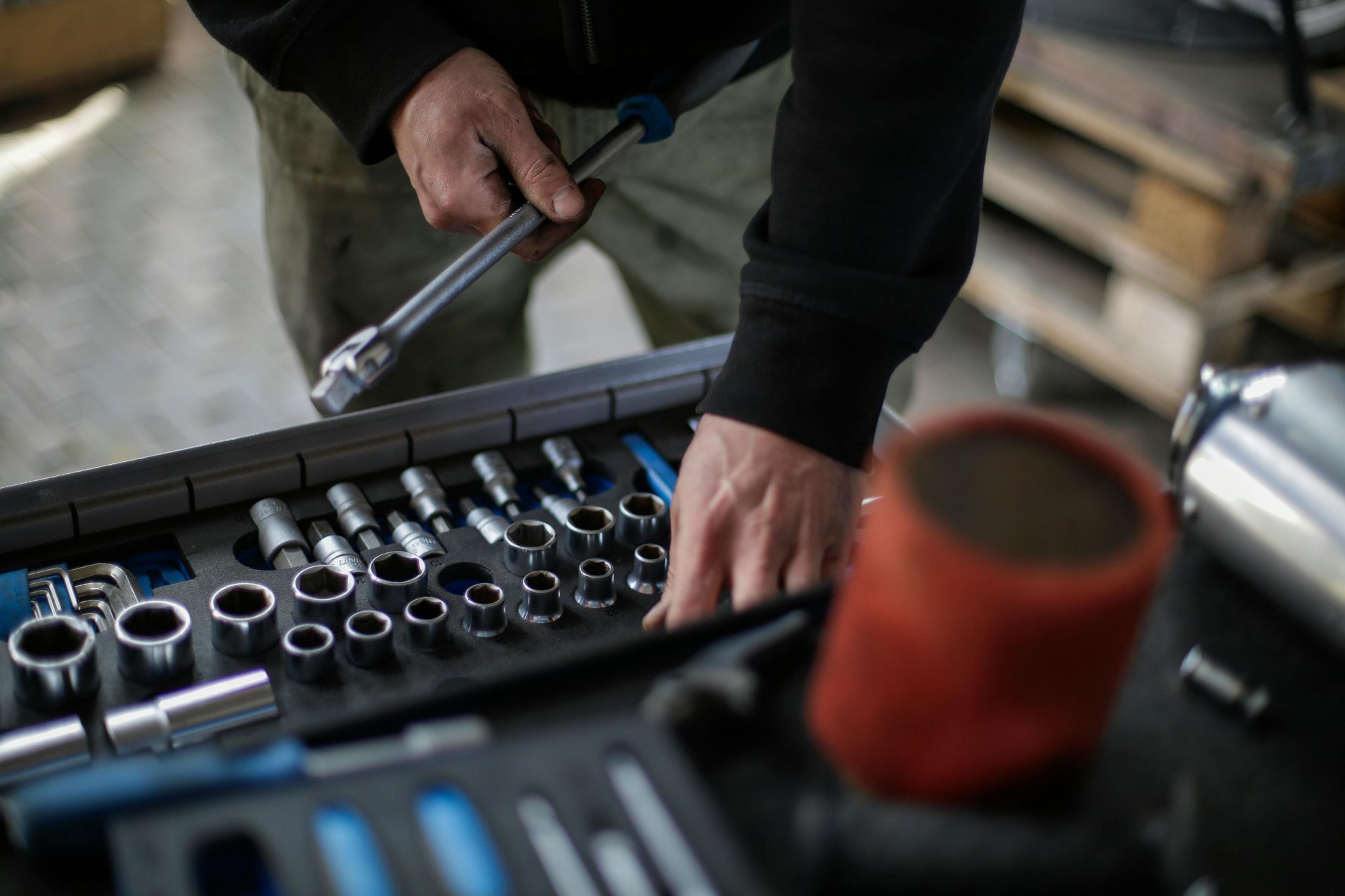 Mechanic using a ratchet wrench over a socket set on a workbench