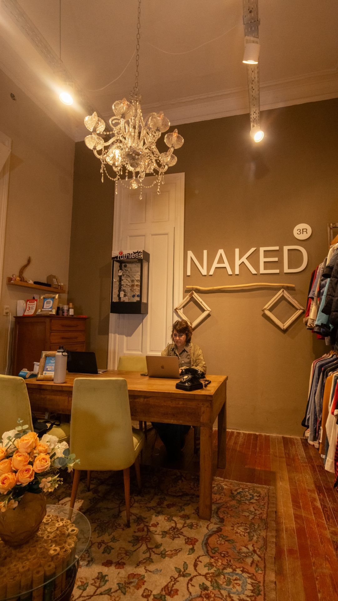 Interior acogedor de estilo boutique con lámpara de araña, mesa de madera, flores y decoración de pared