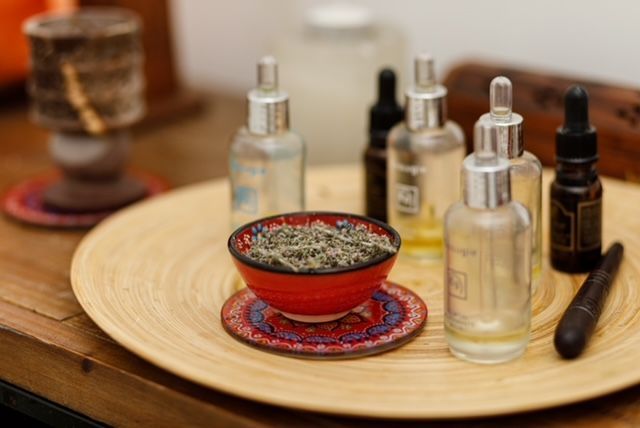 Una bandeja de madera llena de botellas de aceites esenciales y un cuenco de lavanda.