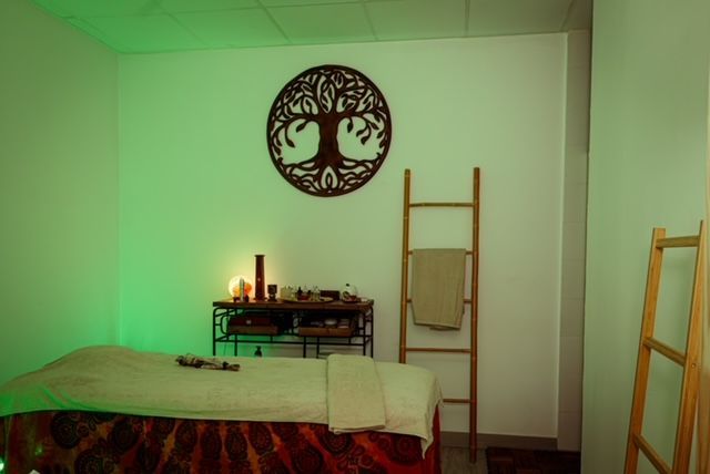 Una mesa de masajes en una habitación con un árbol de la vida en la pared.