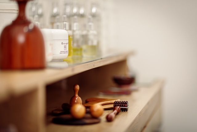 Una cómoda de madera con un jarrón y botellas encima.