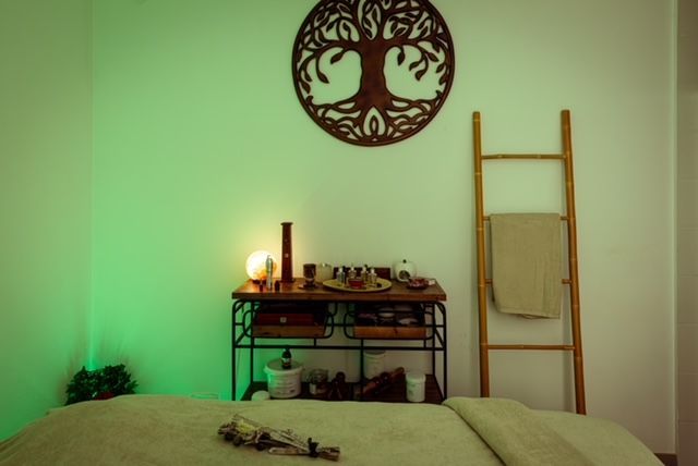 Una mesa de masajes en una habitación con un árbol de la vida en la pared.