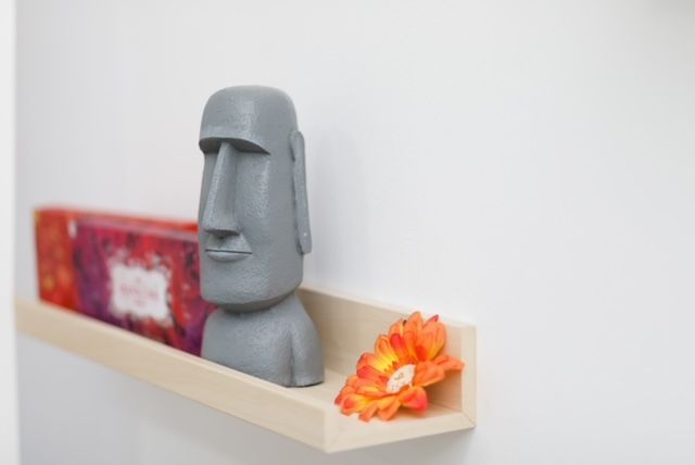 Un estante con una estatua y una flor encima.