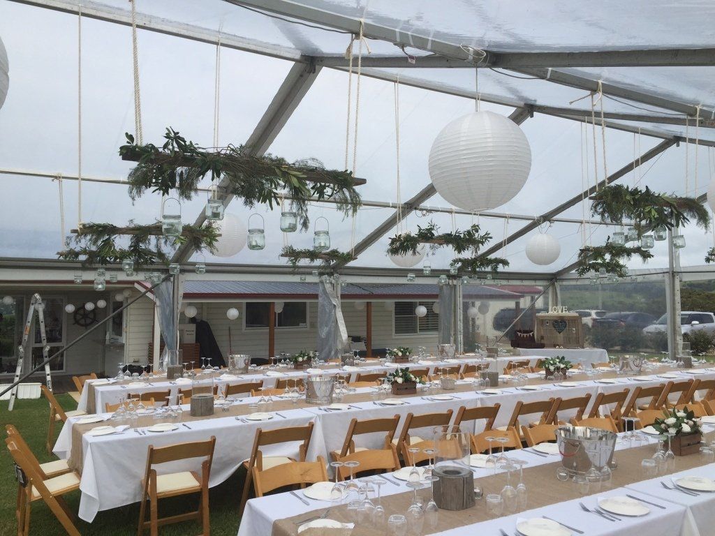 A clear tent with tables and chairs set up for a wedding reception