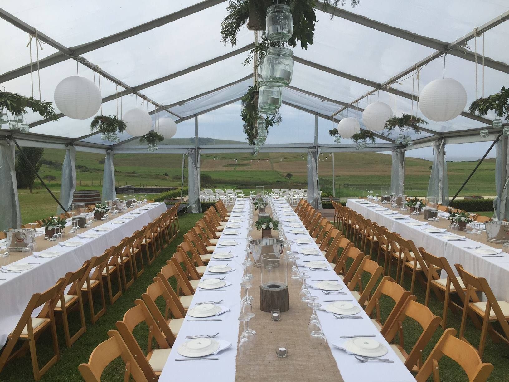 A long table and chairs under a clear tent.