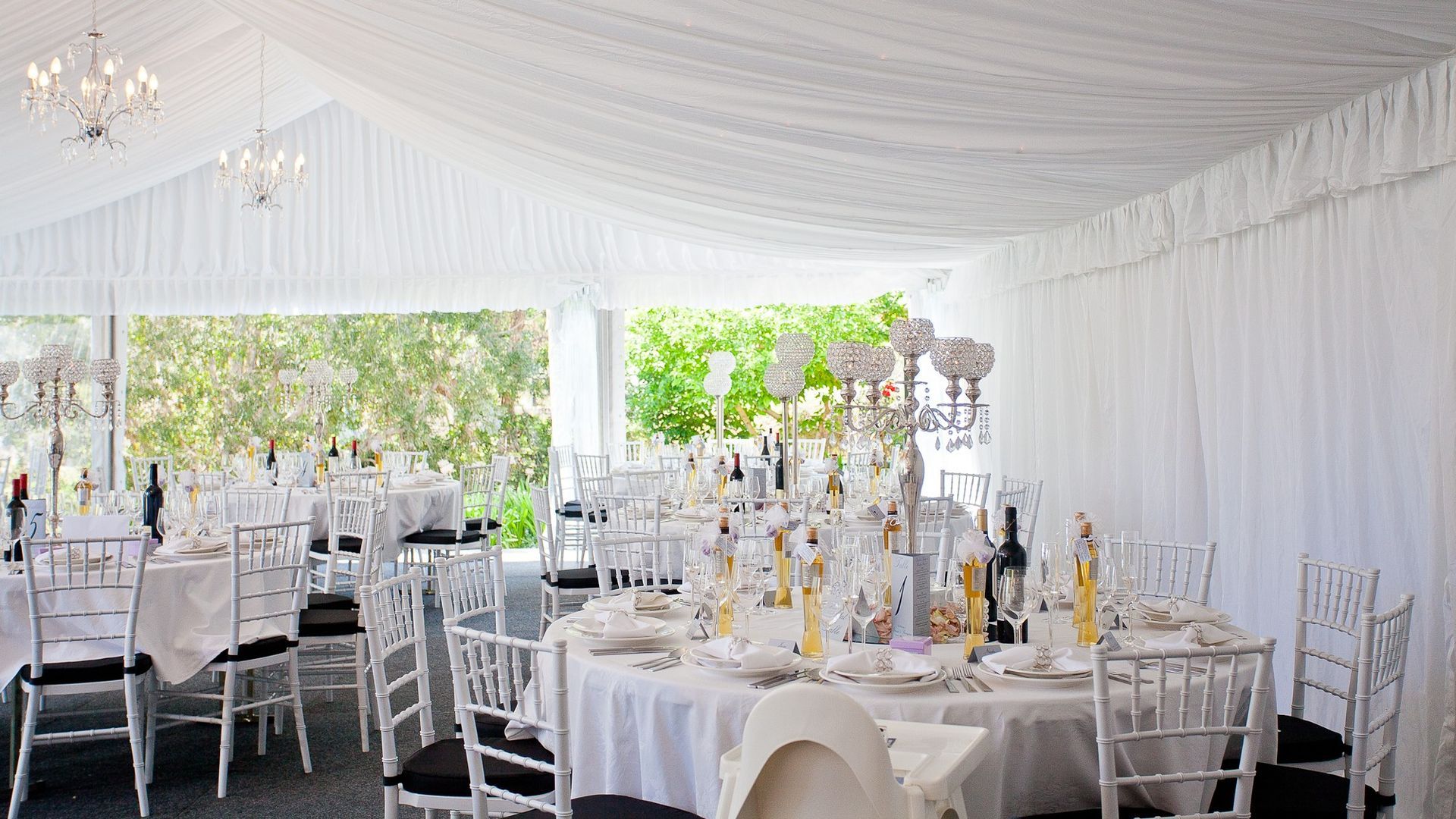 A large white tent with tables and chairs set up for a wedding reception.