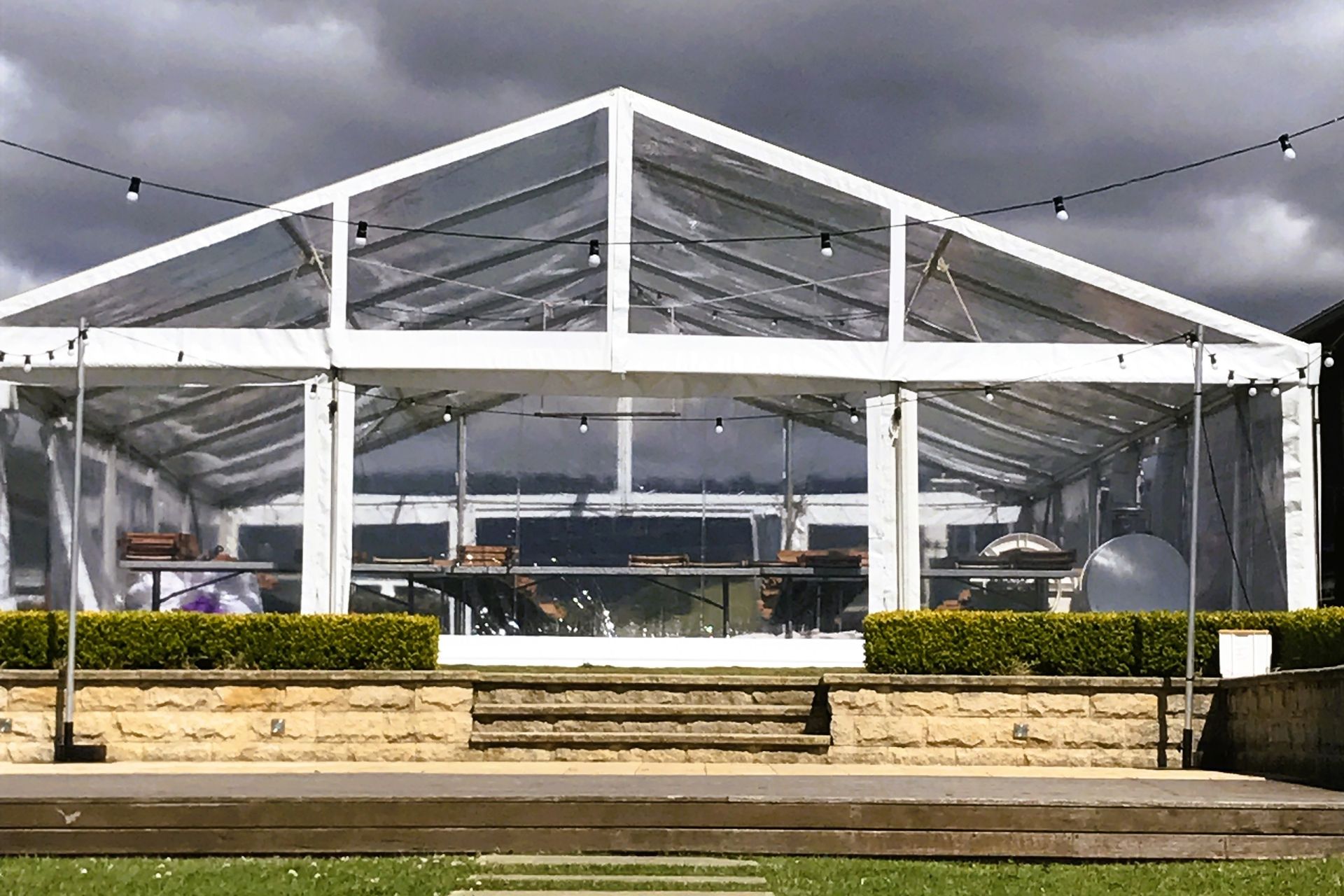 A large clear tent is sitting on top of a lush green field.