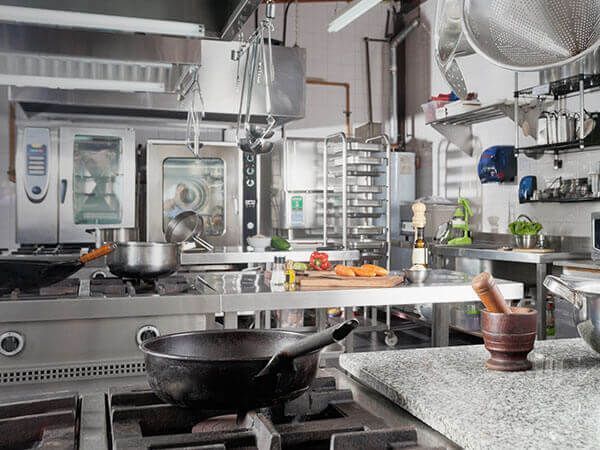 A kitchen with stainless steel appliances and a wok on the stove.