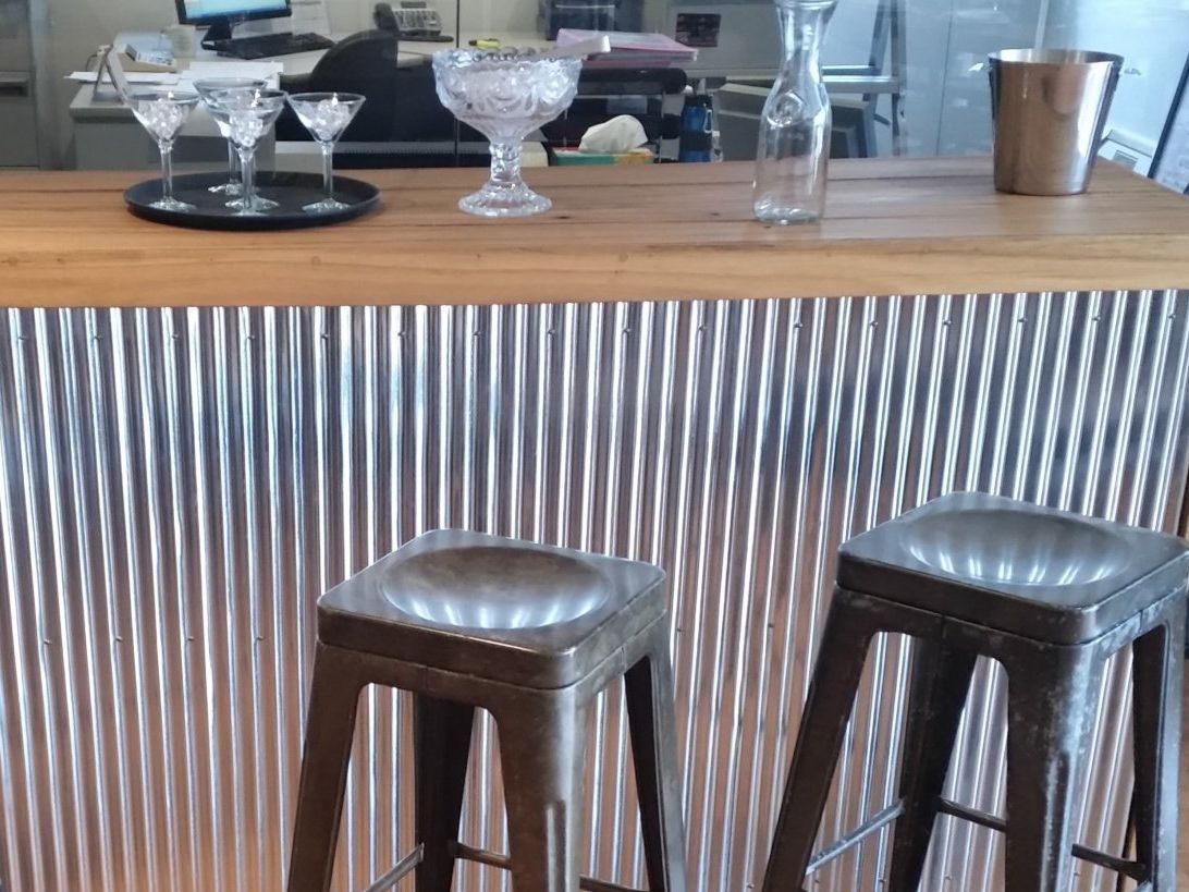 A bar with two stools and two martini glasses on it.