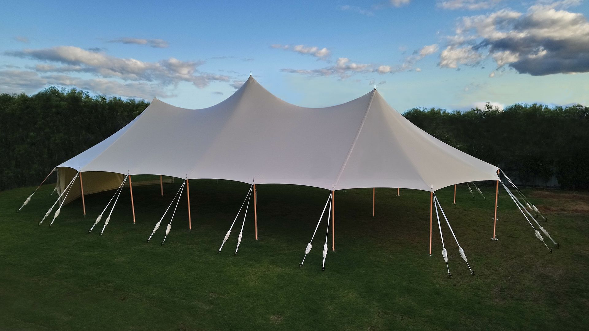 A large white tent is sitting in the middle of a grassy field.