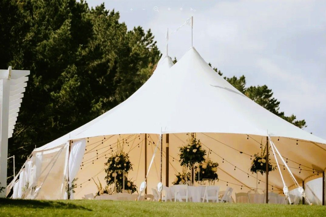 A large white tent is sitting on top of a lush green field.