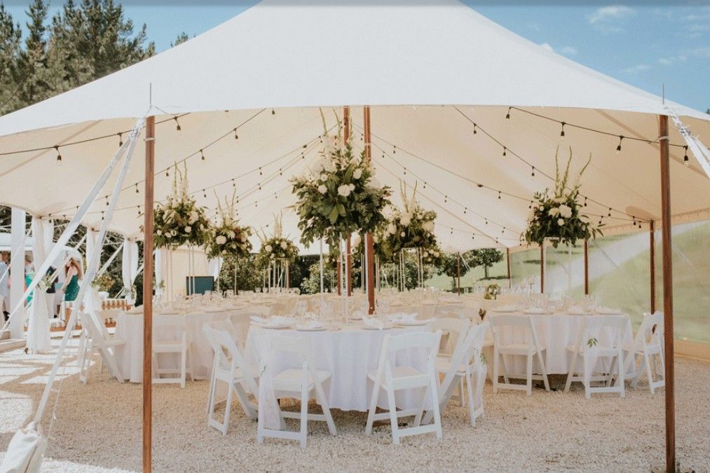 A large white tent with tables and chairs underneath it.