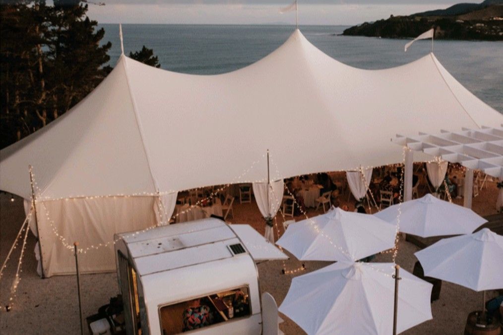 An aerial view of a large white tent with umbrellas in front of it.