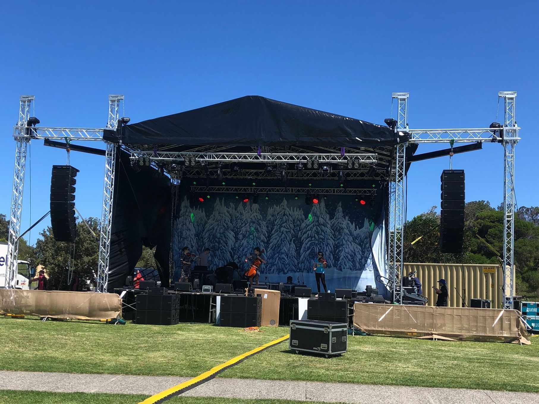 A large stage is being set up for a concert in a park.