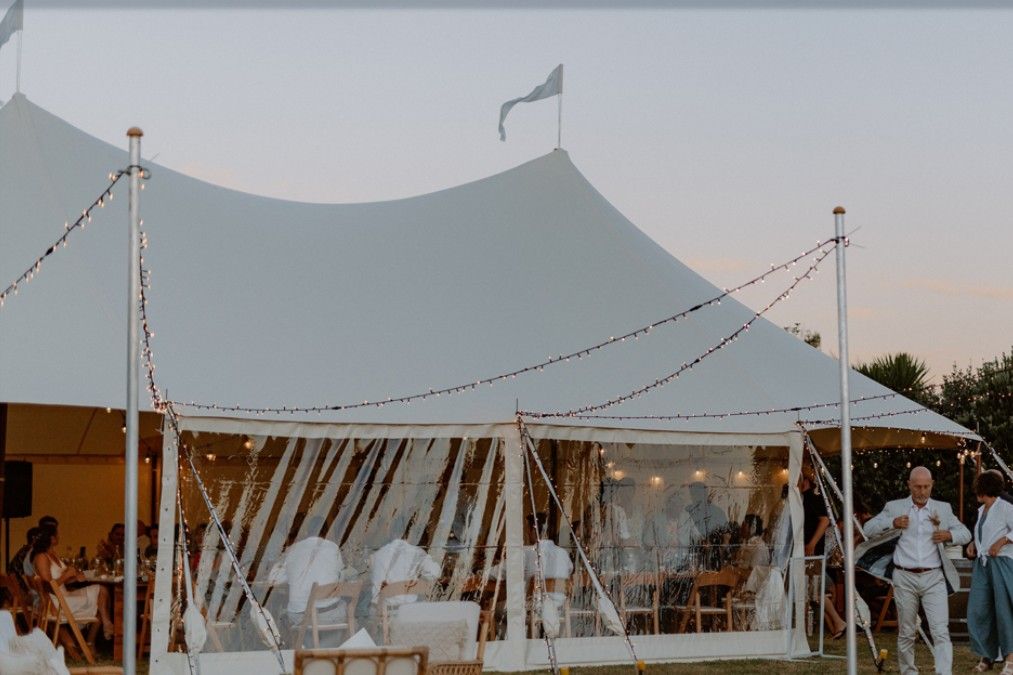 A man is standing in front of a large white tent.