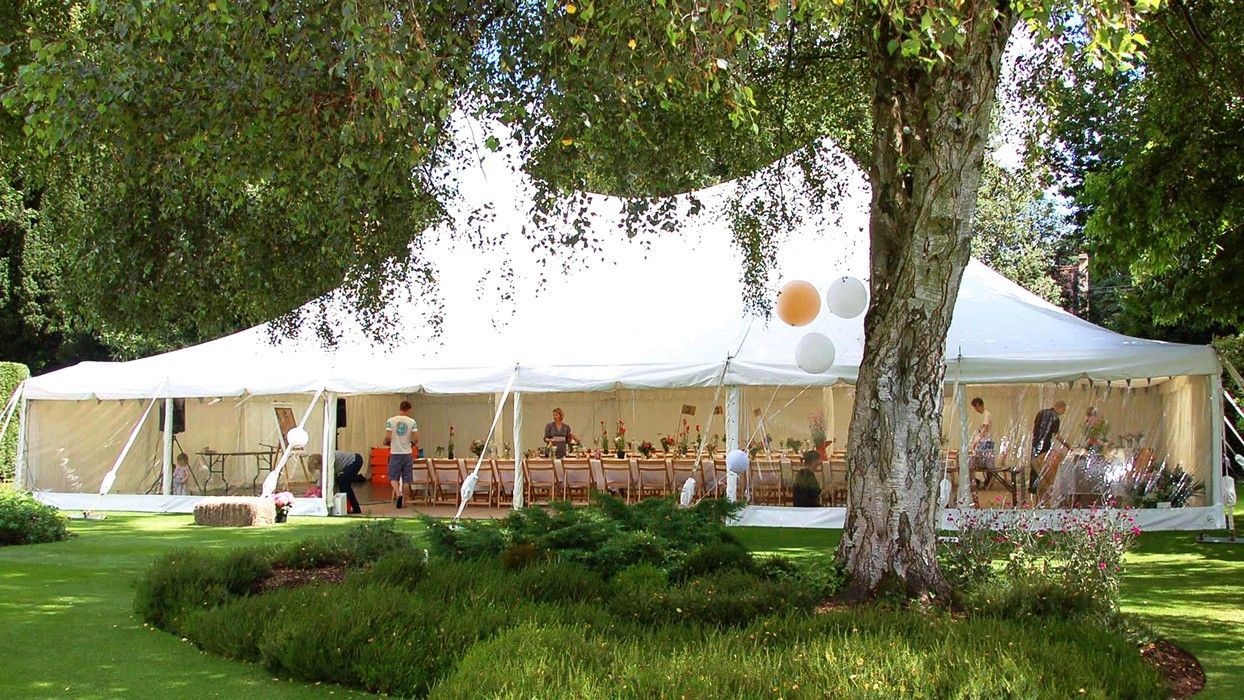 A large white tent is sitting in the middle of a lush green field.