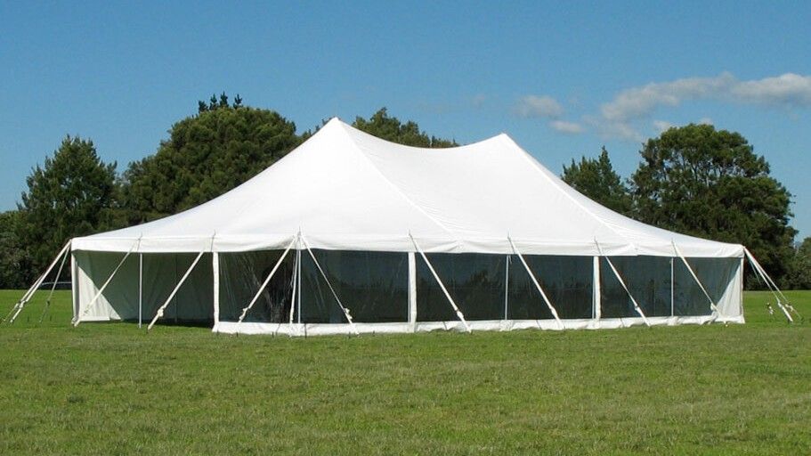 A large white tent is sitting in the middle of a grassy field