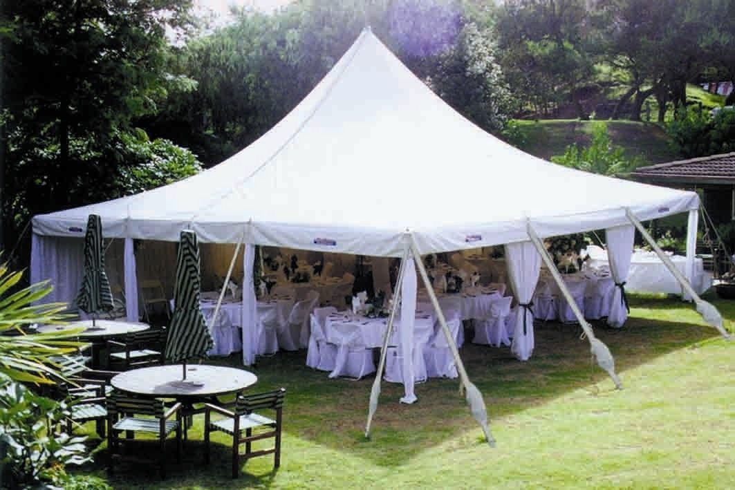 A large white tent with tables and chairs underneath it