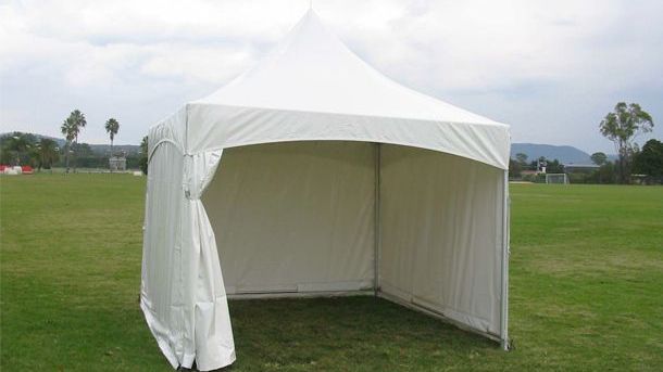 A white tent is sitting in the middle of a grassy field.